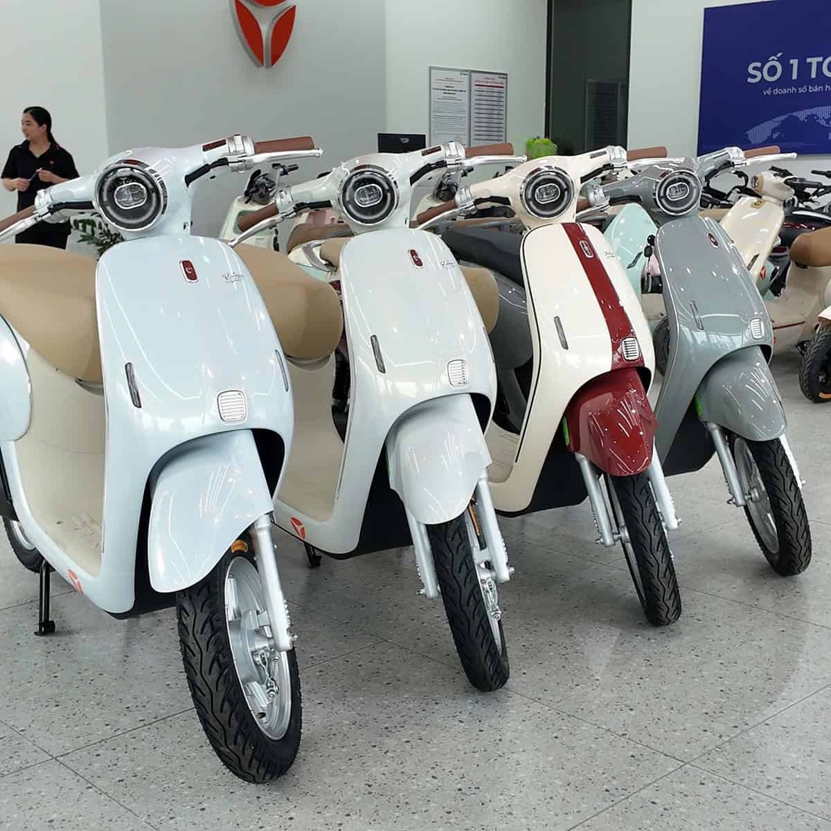 Nhiều xe máy điện cổ điển màu pastel trưng bày trong showroom.