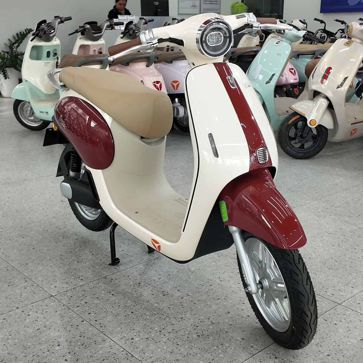 Xe máy điện kiểu cổ điển màu kem và đỏ trong showroom.