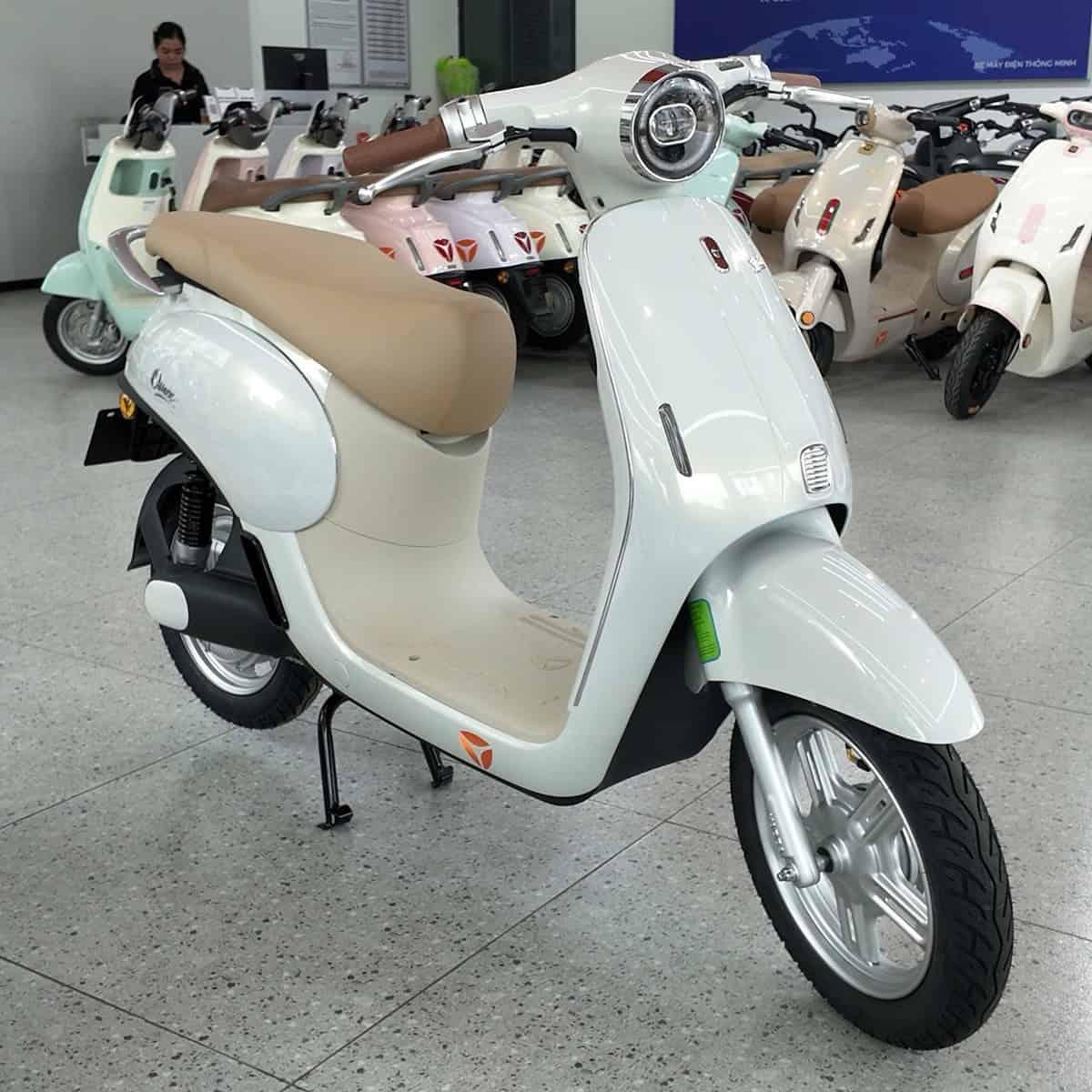 Xe máy điện kiểu cổ điển màu trắng với yên da be trong showroom.